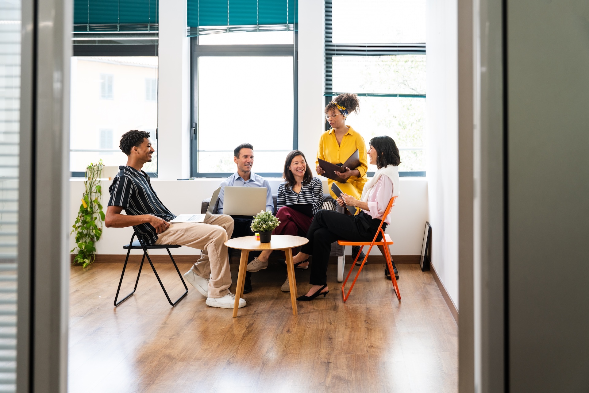 Five cheerful colleagues are discussing work during a productive meeting in a contemporary office space